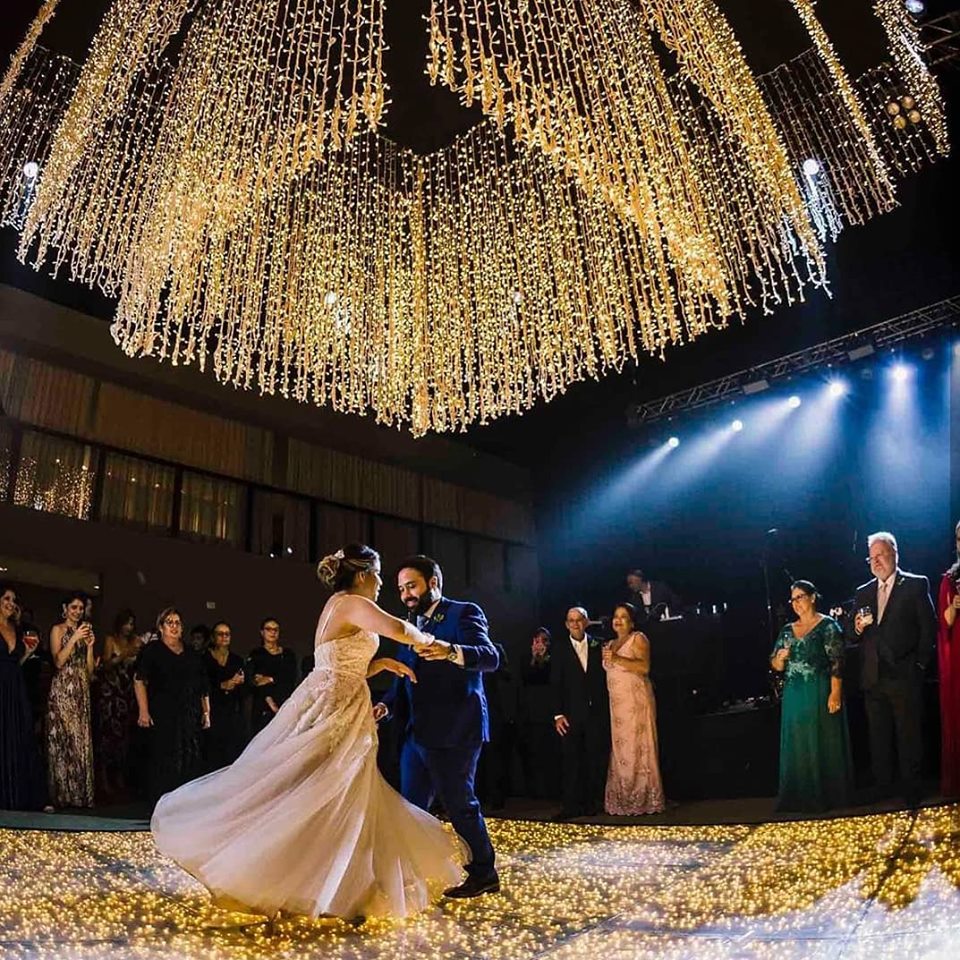 Casamento com iluminação de mega lustre de luzinhas e piso flores